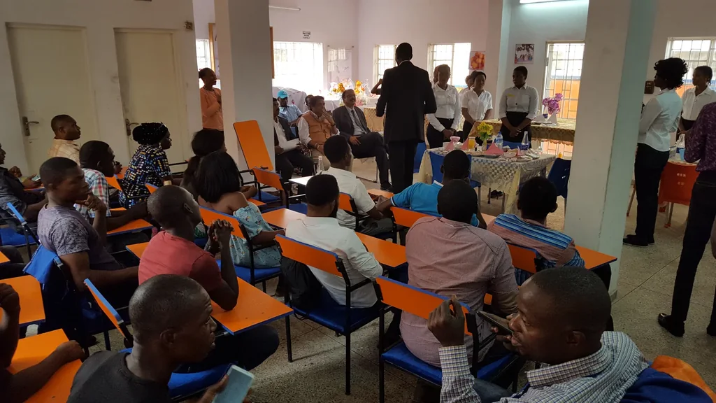 A seated audience watches a presentation around a table in a classroom.