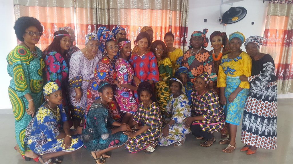 A group in colourful patterned clothing poses together indoors.