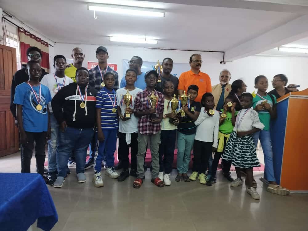 Adults and children pose together indoors, with several people wearing medals.