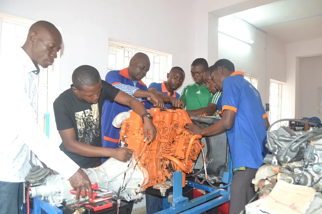 A group gathers on both sides of an engine training stand during a practical demonstration.