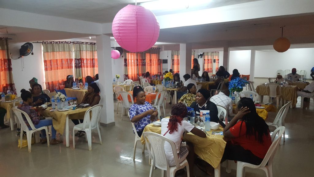 People gather around tables in a decorated hall.