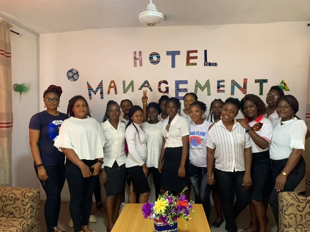 A larger group poses beside a table in the Hotel Management room.
