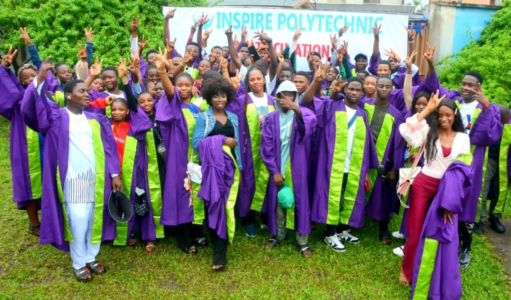 A group in purple and green academic gowns celebrates outside an Inspire Polytechnic matriculation banner.