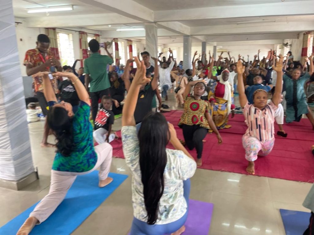 Participants stretch with raised arms on mats during a group exercise session.